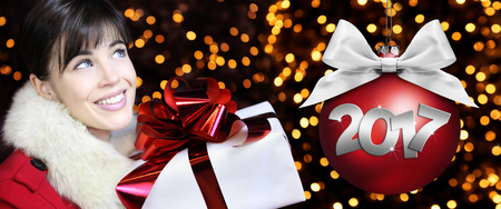 woman with Christmas gift package, smiling and looks up