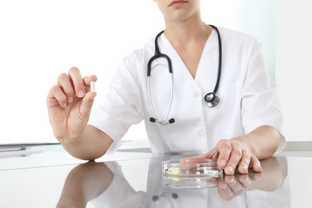 Doctor holding pill medicine close up on desk. Health care and medical conceptの写真素材