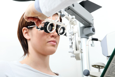 optician with trial frame, optometrist doctor examines eyesight of woman patient