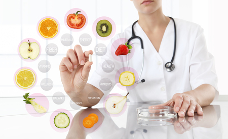 healthy food supplements concept, Hand of nutritionist doctor showing pill on symbols fruits background.の写真素材