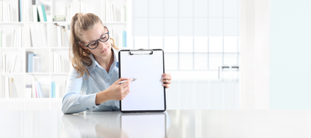 woman hands showing clipboard with a pen, sitting in office desk.の写真素材