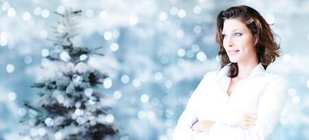 christmas theme, business smiling woman on blurred bright lights background, banner template with copy space.の写真素材