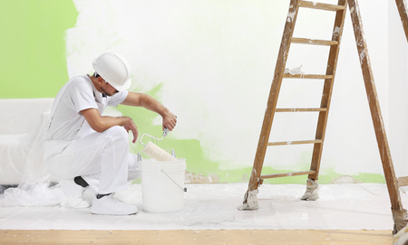 painter man at work takes the color with roller paint brush from the bucket.の写真素材