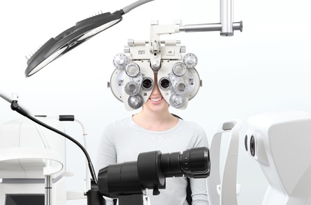 optometrist exam, eyesight  woman patient with phoropter in optician office.