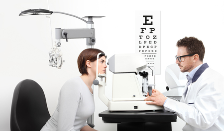 optometrist examining eyesight  patient in optician office on white background.の写真素材