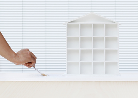 Painter man hand with paint brush painting white house model on board, home service concept, blank banner template with copy space.の写真素材