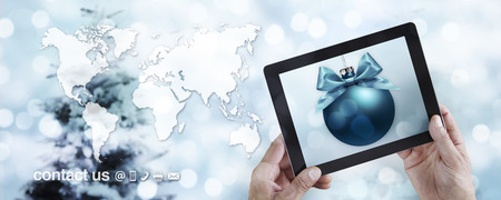 Christmas travel and online shopping concept, hands showing digital tablet with ball on blurred...