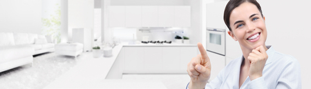 smart home automation smiling woman hand touch screen on kitchen and living room background.の写真素材