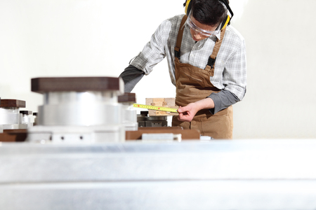 carpenter man works with wooden planks in the joinery, measure with meter, with computer numerical control center, cnc machine,  isolated on a white backgroundの写真素材