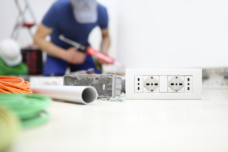 electrician at work with silicon gun in hand, install socket, electric circuits, electrical wiring,の写真素材