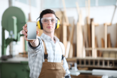 carpenter man show the mobile phone isolated on carpentry backgroundの写真素材
