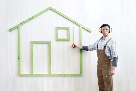 house construction renovation concept handyman carpenter worker man with measure and show model of a wooden house, custom solutions,の写真素材