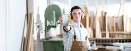 carpenter man show the mobile phone isolated on carpentry background ..の写真素材