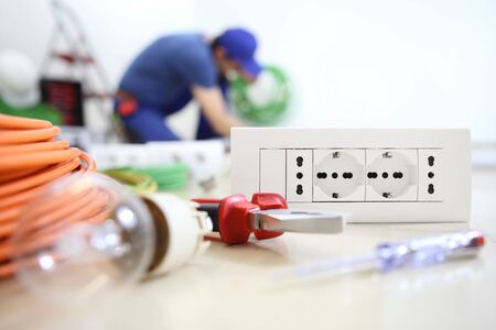 electrician work with electric equipment in the foreground, bulb, tools and socket, electric...