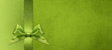 christmas gift card with green ribbon bow on green background, copy space templateの写真素材