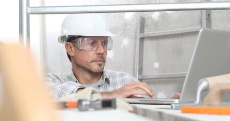 man work, professional construction worker with computer, plastering tools on scaffolding, safety...