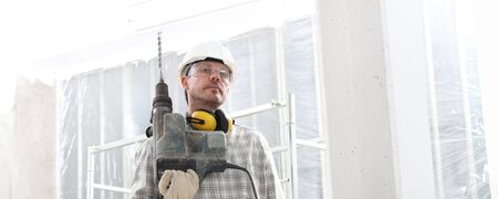 man with electric pneumatic drill, professional construction worker with safety hard hat, hearing...