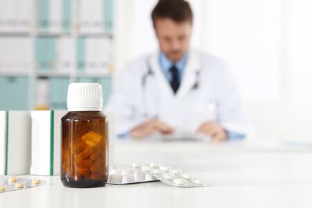 pills, blister, bottle and tablets boxes medicine on medical desk office with doctor on background.の写真素材