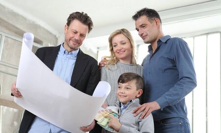 Architect showing house design plans to a family with child. Meeting at interior construction site...