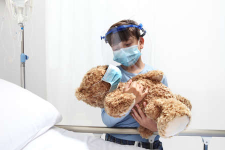 Child in the hospital with a medical mask on face near the bed, corona virus covid 19 protection conceptの写真素材