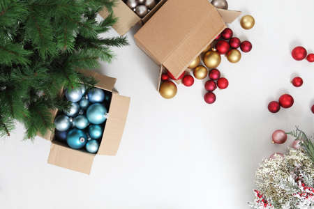 Christmas tree and cardboard boxes full of christmas balls and decorations, isolated on white floor,...