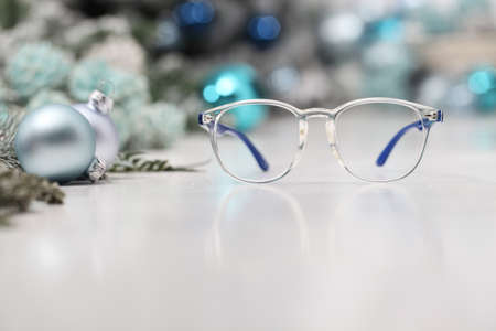 christmas eyeglasses blue spectacles isolated on white table with balls and decorations useful as a greeting gift card template with copy spaceの写真素材