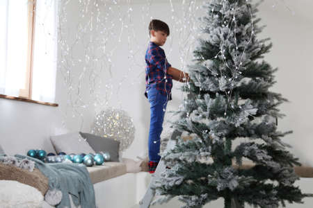 child decorate the christmas tree on ladder at homeの写真素材