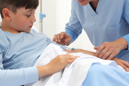 Child lying in bed in hospital room looking at his harm with a drip in it and nurse medicating himの写真素材