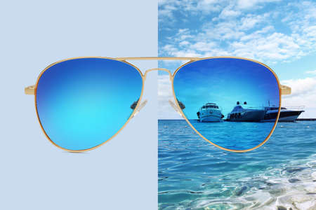 aviator sunglasses isolated on blue and summer background with boats on the sea and blue sky, concept of polarized protective lensesの写真素材