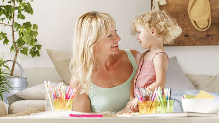 smiling mom hugs her daughter child, preschool learning activities at home, concept of healthy growing, support from caring adults to help develop the habits they need to thrive in school and beyond.の写真素材