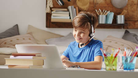smiling student boy studying on the computer at remote school on the web, concept of browsing and searching the internet or other activities such as social media or online games or entertainmentの写真素材