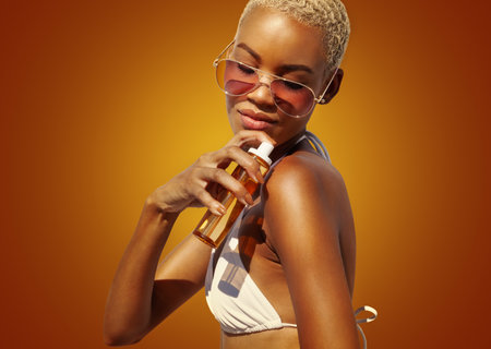 woman with sunglasses applying sunscreen lotion to shoulder skin for care and sun protection,...