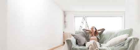 Relaxed Woman on Sofa Reflects on Home Renovation: Trusting Experts for Cleaning, Painting, and Mold Removal. Call Specialized Services or professional workers to Resolve Your Problemsの写真素材