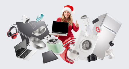 Electronics and appliance store Christmas shopping, smiling woman showing laptop screen and thumb up among household appliances, advertising banner for top offers in sales of Christmas shopping onlineの写真素材