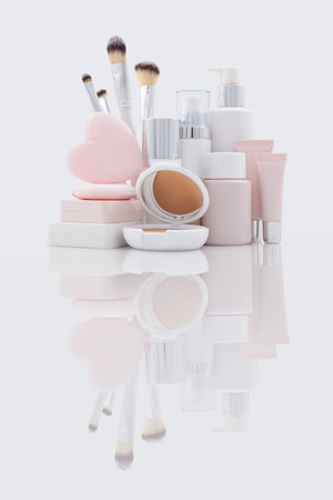 Set of makeup and beauty cosmetics products on a reflective surface. Compact powder, pump bottles, tubes, puff and brushes. Advertising for beauty store deals, online shopping and Christmas gift ideasの写真素材