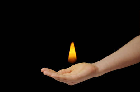 Yellow little tongue of flame on girl's hand isolated on blackの写真素材