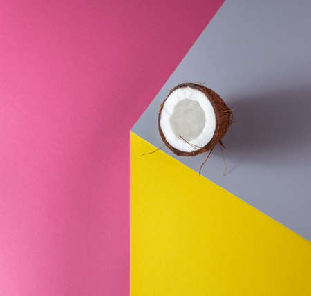 Sliced ââcoconut on a gray background. Against pink and yellow background. Minimal concept.の写真素材
