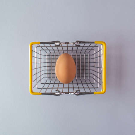 Easter egg in a basket on a grey  background with creative copy space. Minimal Easter holiday conceptの写真素材