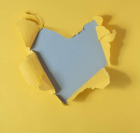 Vivid yellow  torn paper. Heart-shaped burst hole background. Minimal abstract colorful wallpaper conceptの写真素材