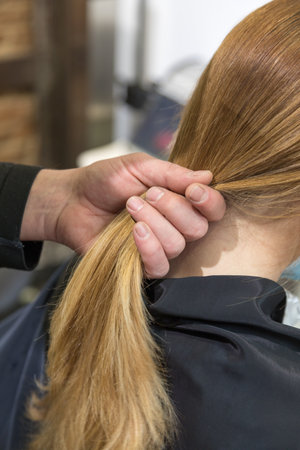 woman being combed by hairdresser with spray and blow dryer in front of mirror in modern retro hair salonの写真素材