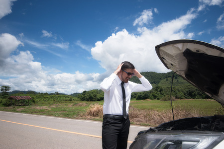 Stressed young man with broken car in the middle at the countryside street.の写真素材