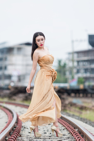Asian woman model wearing a beautiful dress posting in the rail way at train station,Beautiful dress fashion at train station.の写真素材