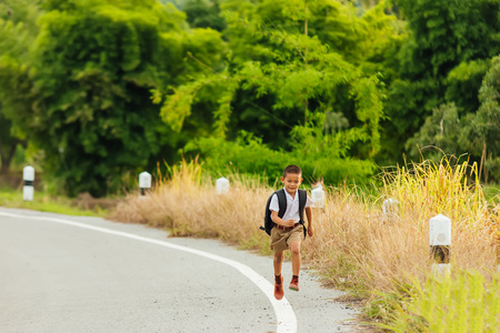 Asian student,Asian student with bag are running through the fields back home and nature view.の写真素材