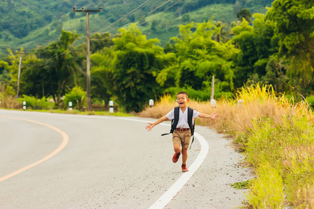 Asian student,Asian student with bag are running through the fields back home and nature view.の写真素材