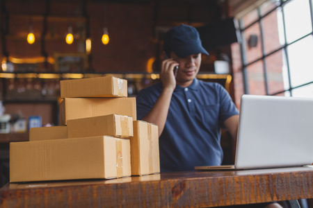 Asia delivery man are holding a cardboard box delivery to his customer.Delivery man are checking customer from the mobile.の写真素材