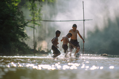 Asian children play soccer in the river,Sport plays an important role in rural and regional Thailand,Sport are the predominantly or exclusively played in rural areas,Thailand football.の写真素材