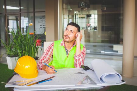 Waiting for inspiration.Engineers Are sitting and thinking about work and looking away while sitting at his working place.の写真素材
