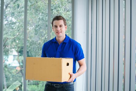 Delivery man in blue uniform of delivery service,Online selling, e-commerce,Shipping concept.の写真素材