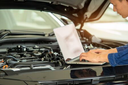 Close up hand Technician use computer Analyze car problems and repairs the car in the garage,Mechanic check car concept.の写真素材