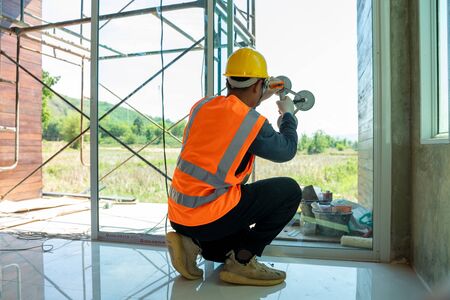 Glass installation technician,Close up male industrial worker at window installation at construction site.の写真素材
